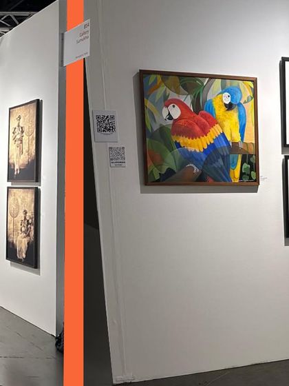 A side view of our Seattle booth, highlighting the striking parrot painting by Senaka Senanayake and other works. The layout is designed to catch the eye and draw visitors in.