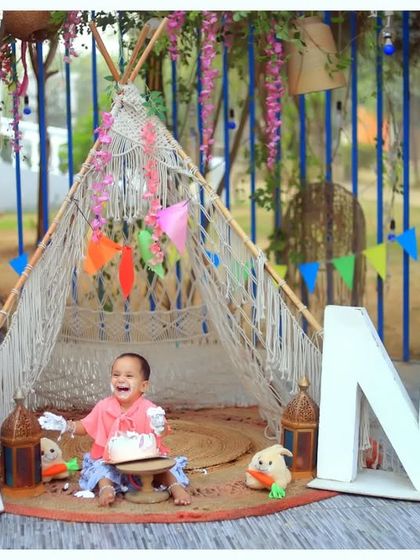 A beautiful outdoor first birthday setup with a boho-chic teepee and large 'ONE' letters. We create stunning milestone portraits in natural settings.