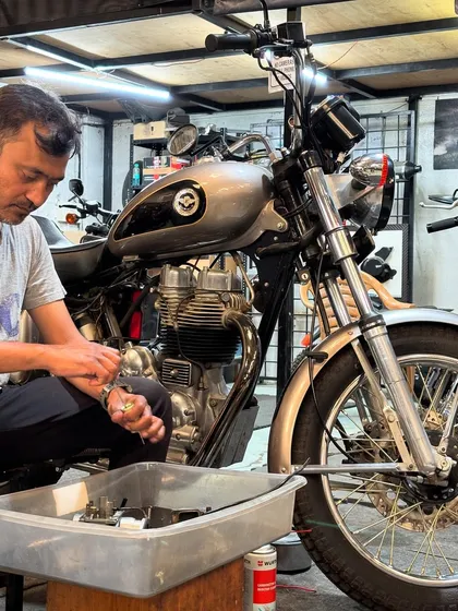 Working on the carburetor of a classic Royal Enfield. These older bikes require a delicate touch and deep mechanical knowledge.