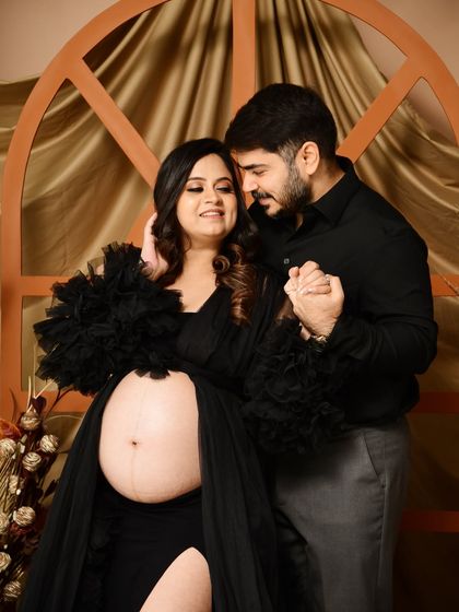 An intimate close-up shot focusing on the couple's connection and the beautiful baby bump. The open-belly black gown is a popular choice for highlighting this special time.