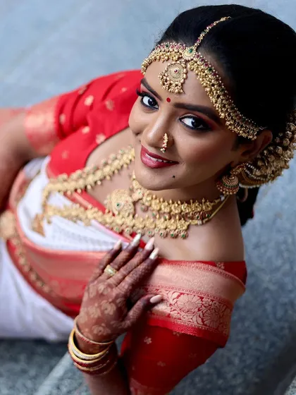 A beautiful high-angle shot of a South Indian bride in her traditional red and white saree. This perspective highlights the stunning temple jewelry and the elegance of the moment.