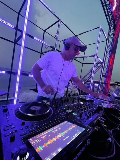 Setting the vibe for a sundowner wedding event. This shot captures me in my element, mixing tracks on my Pioneer DJ setup against a beautiful sunset, with a custom lighting rig ready for the night ahead.