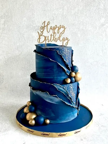 A modern and artistic cake in deep blue. The design features a "fault line" effect with gold and blue textures, creating a geode-like appearance.