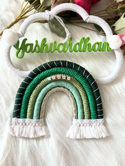 A close-up shot of the "Yashwardhan" name hanging, focusing on the neatly wrapped rainbow and the personalized name.