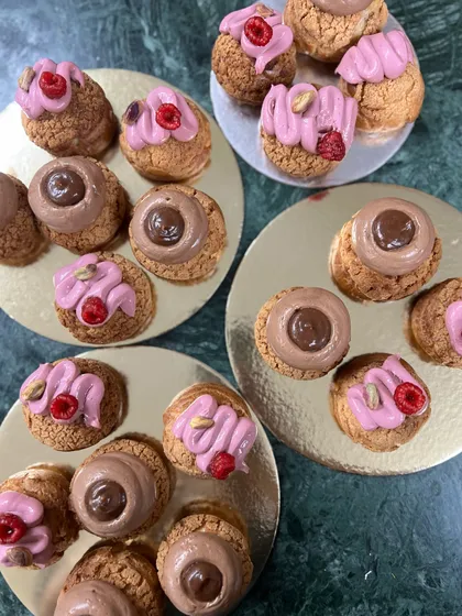 A close-up of my favorite choux pastries. I offer them in several flavors, including the rich Chocolate & Caramel and the fresh, vibrant Pistachio & Raspberry. Each one is a little bite of heaven.