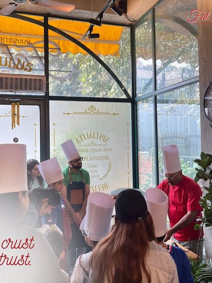 In crust we trust. A shot of me teaching a group of enthusiastic learners, all in their chef hats, the secrets to a perfect pizza base.