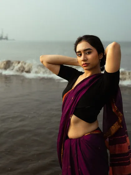 A powerful pose that highlights the model's confidence and the striking silhouette of the saree against the waves.