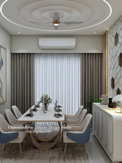 A dining room with a circular false ceiling design that mirrors the round dining table. The wall features a geometric pattern with hexagonal mirrors, adding a modern, glamorous touch.