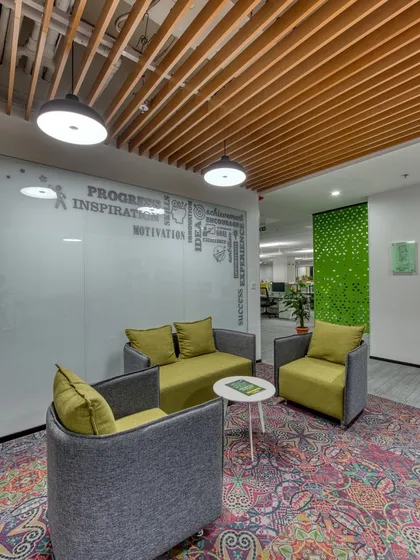 A collaboration seating area in an open office. The colorful patterned rug and word-cloud graphic on the glass wall add personality to the space.