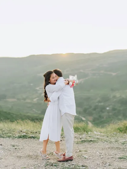 A heartfelt embrace at sunset on a hilltop, capturing the raw emotion and stunning views.