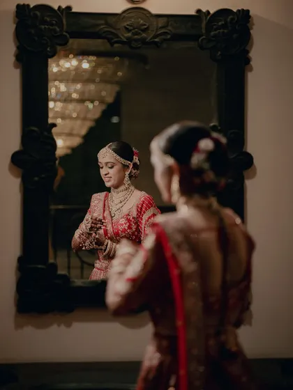 Another beautiful mirror shot, capturing the bride's reflection and the intricate details of her hair and makeup.