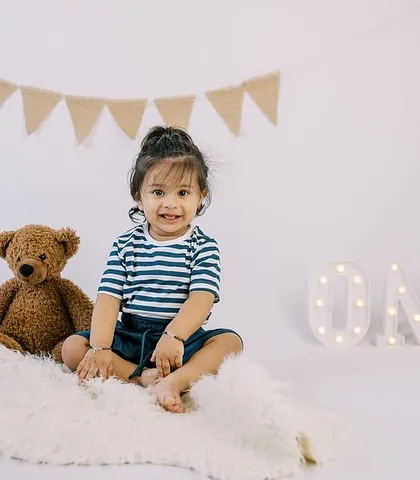 A sweet portrait of the birthday boy sitting with his teddy bears and the "ONE" sign, a classic and adorable first birthday photo.