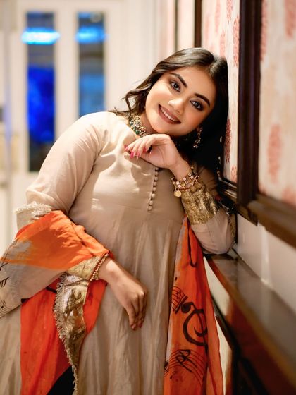 A charming and relaxed portrait of a model leaning against a wall, her warm smile lighting up the frame. A perfect blend of elegance and ease.