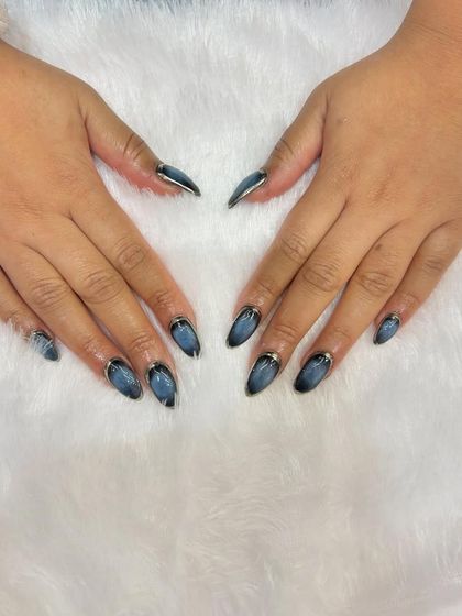 A moody and sophisticated cat-eye manicure. The dark, shimmery base is accented with a delicate silver line at the cuticle for a polished finish.