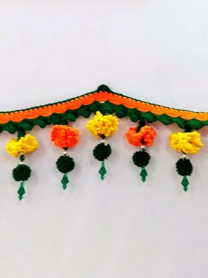 This Zendu toran features both yellow and orange marigolds with hanging green pom-poms, creating a full and festive look.