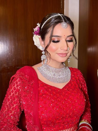 A close-up of Anjali's beautiful floral hair bun and soft eye makeup. The combination of red roses and baby's breath in her hair adds a touch of romance.
