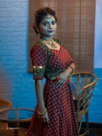 A profile shot of a model in a traditional outfit, showing the indoor setting. The composition creates a sense of depth and context.