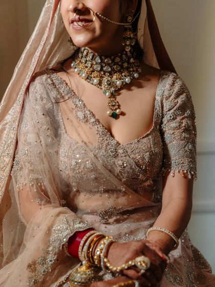 A detailed shot capturing the grace of the bride. The focus is on the intricate details of her outfit and the soft, complementary makeup.