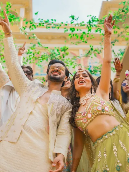 The bride and groom dance with abandon, their hands in the air, during their high-energy Haldi celebration.