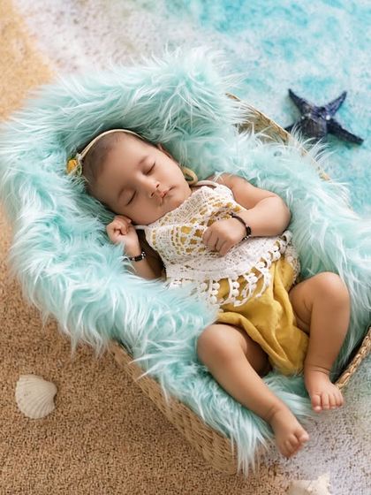A sleeping mermaid dreaming of the sea. This creative setup with sand, starfish, and a cozy basket creates a magical beach scene right in the studio.