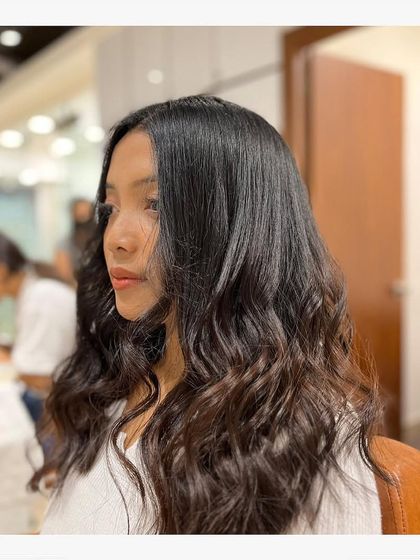 A client with long, dark hair styled into soft, natural-looking waves. This simple yet elegant style shows off the health and shine of her hair.