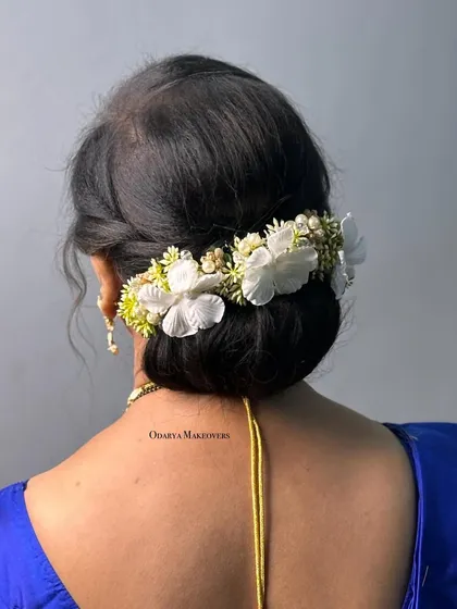 A classic low bun decorated with a beautiful floral hairpiece. This is a sophisticated hairstyle for mothers of the bride or groom.