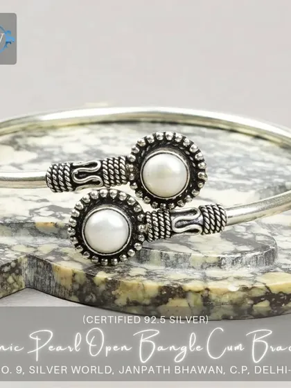 An ethnic open bangle featuring two original mother-of-pearl studs in a granulated silver setting. A beautiful blend of classic and traditional design.
