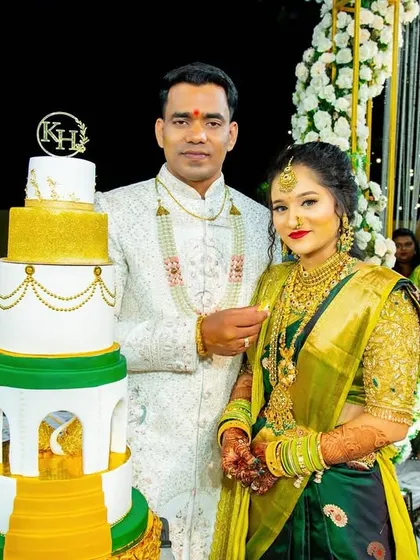 A happy couple posing with their grand cake during their engagement ceremony.