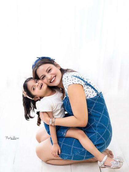 A big, happy hug between a mother and her daughter. Their joyful expressions and casual denim outfits make this a relatable and heartwarming photo.