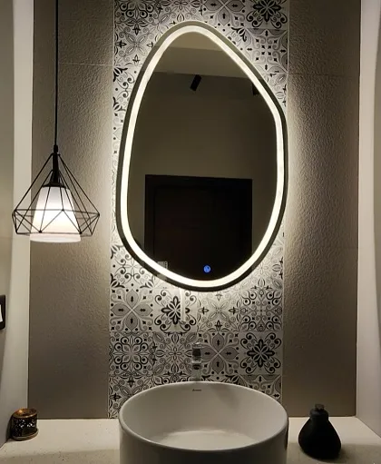 A modern powder room with a unique backlit mirror, a vessel sink, and a patterned tile accent wall.