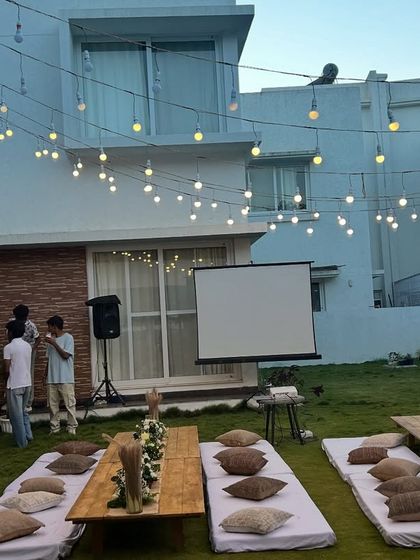 The movie night party in full swing, with string lights overhead creating a magical ambiance as guests gather.