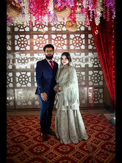 A formal portrait of the bride and groom at their wedding reception. The elegant decor and their classic pose create a timeless memory of their celebration.