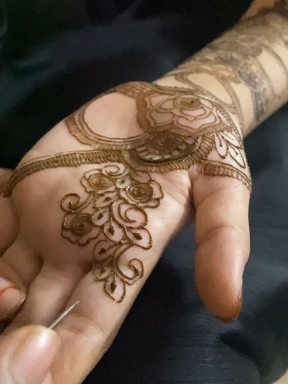 A close-up of me working on a delicate rose pattern in the palm. The fine lines and careful application are key to achieving this soft and romantic floral look.