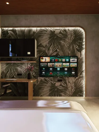 The TV and study unit in the tropical-themed bedroom continues the aesthetic with a leaf-patterned wallpaper and clean wooden shelving. This creates a multi-functional space that remains cohesive in its design.