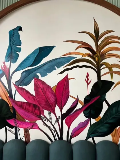 A close-up of the tropical mural headboard. The rich pinks and deep teals of the leaves were layered to create a sense of lushness and depth, making the artwork feel alive.