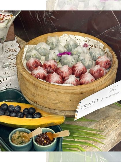 A colourful assortment of dim sums, including pink and white varieties, served in a bamboo steamer. A visually appealing and delicious option for any event.