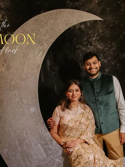 A romantic photo from the Retro Night, with the couple posing on a crescent moon prop, captioned "To the moon and back." 