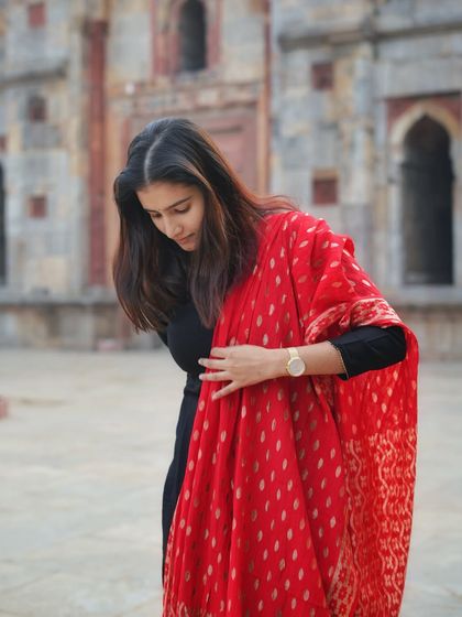 Another beautiful shot focusing on the details of her red Banarasi dupatta. This candid pose highlights the rich texture and design of the traditional fabric.