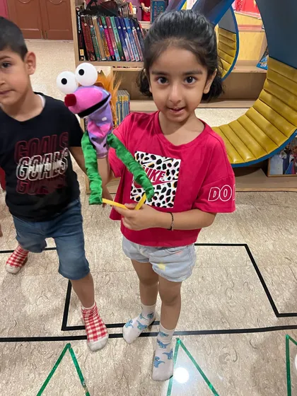 A proud moment for one of our campers, showing off her completed hand puppet. This activity helps develop fine motor skills and encourages creativity.