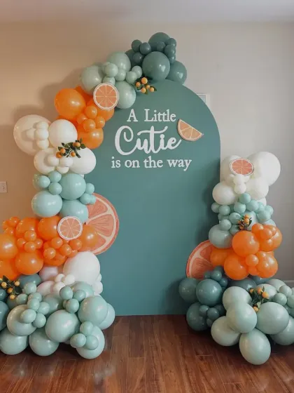 A fresh and unique theme for a baby shower: "A Little Cutie is on the way". This setup uses orange, teal, and white balloons with citrus slice details for a bright and cheerful celebration.