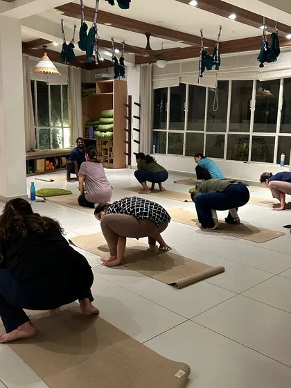 Students practice a deep squat, a foundational pose for hip mobility and grounding.