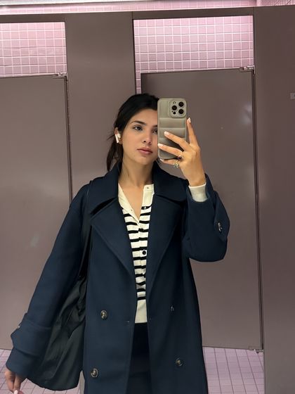 A preppy college look with a striped cardigan and trench coat, showing a more classic campus style.