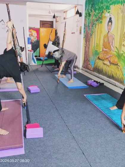 In some sessions, we use props like sticks to assist with alignment and deepen stretches. Here, students are using them to get a better opening in a standing forward bend variation.