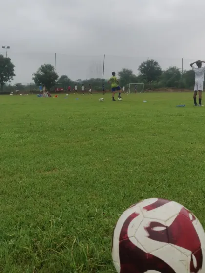 A single ball in the foreground with the training session blurred in the background. A simple image that says "football is life."