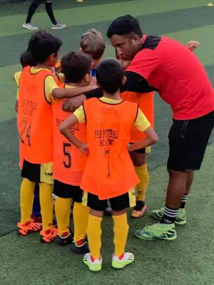 A coach in a huddle with his team. We develop skills, resilience, and teamwork through every aspect of the game.