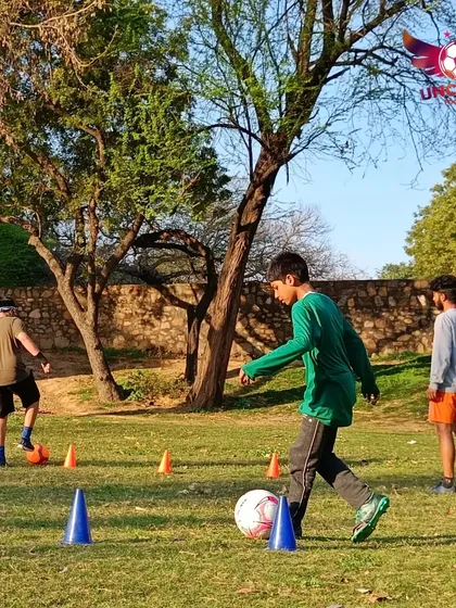Focus and control. A young player carefully navigates a cone drill, mastering the ball control and footwork that forms the foundation of a great footballer. Every touch matters.