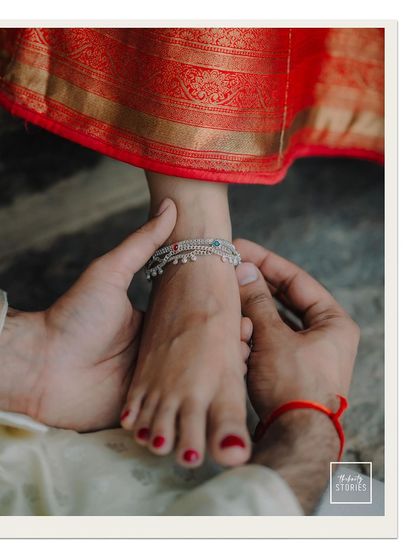 A close-up on a tender moment, focusing on the traditional anklet. I believe in capturing these small, symbolic details that add depth to your love story.