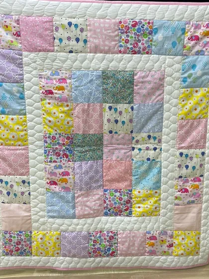 A soft and sweet baby quilt made with pastel-colored patchwork squares.