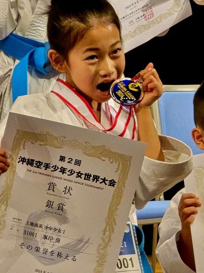 A young competitor joyfully bites her silver medal, a classic champion's pose. Her happiness and pride are what make all the hard work worthwhile.