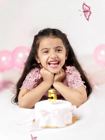 A big, joyful laugh that lights up the room! This is the happiness of turning five, complete with a little cake and a candle to make a wish.